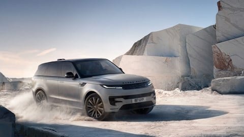 Range Rover Sport Electric (2026): front three quarter cornering, driving around a quarry, matte grey paint