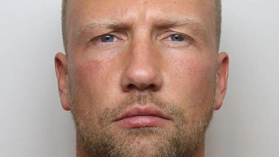 Mugshot of man with short hair and beard