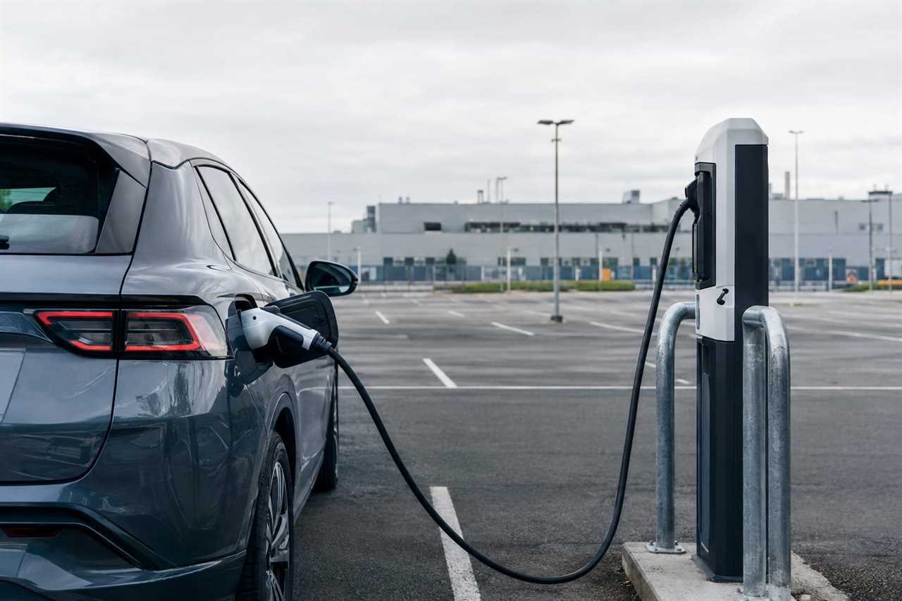 An electric car charging outside a car factory.